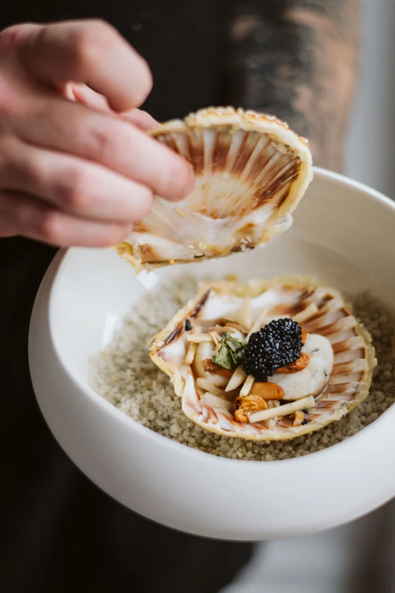 Coquille Saint-Jacques garnie d’une noix, de girolles et de caviar, couvercle feuilleté soulevé, lit de gros sel
