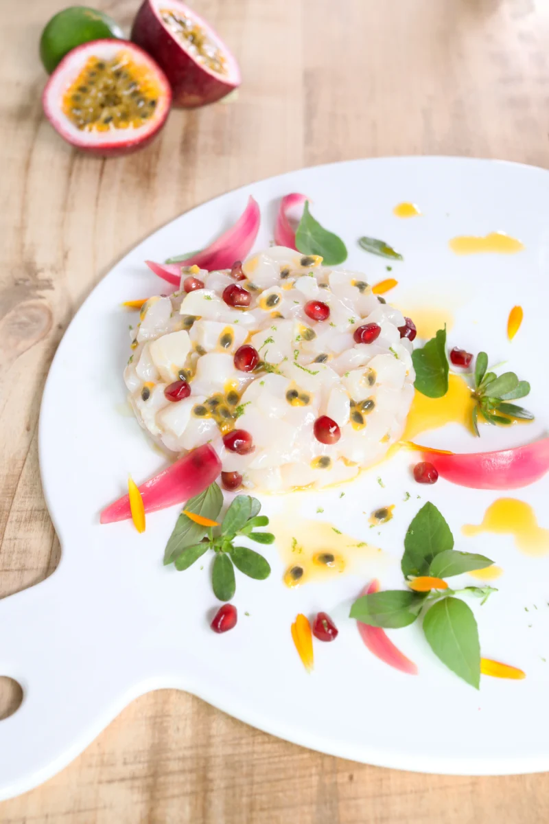 Tartare de noix de Saint-Jacques en cubes, graines de fruit de la passion et grains de grenade, lamelles d’oignon rose