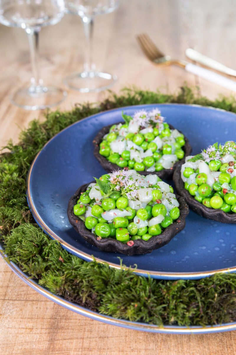Tartelettes noires à l’encre de seiche garnies de petits pois, de cubes de noix de Saint-Jacques et de fleurs de menthe